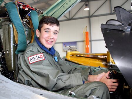 Visiteur assis dans le cockpit d’un avion de chasse au musée